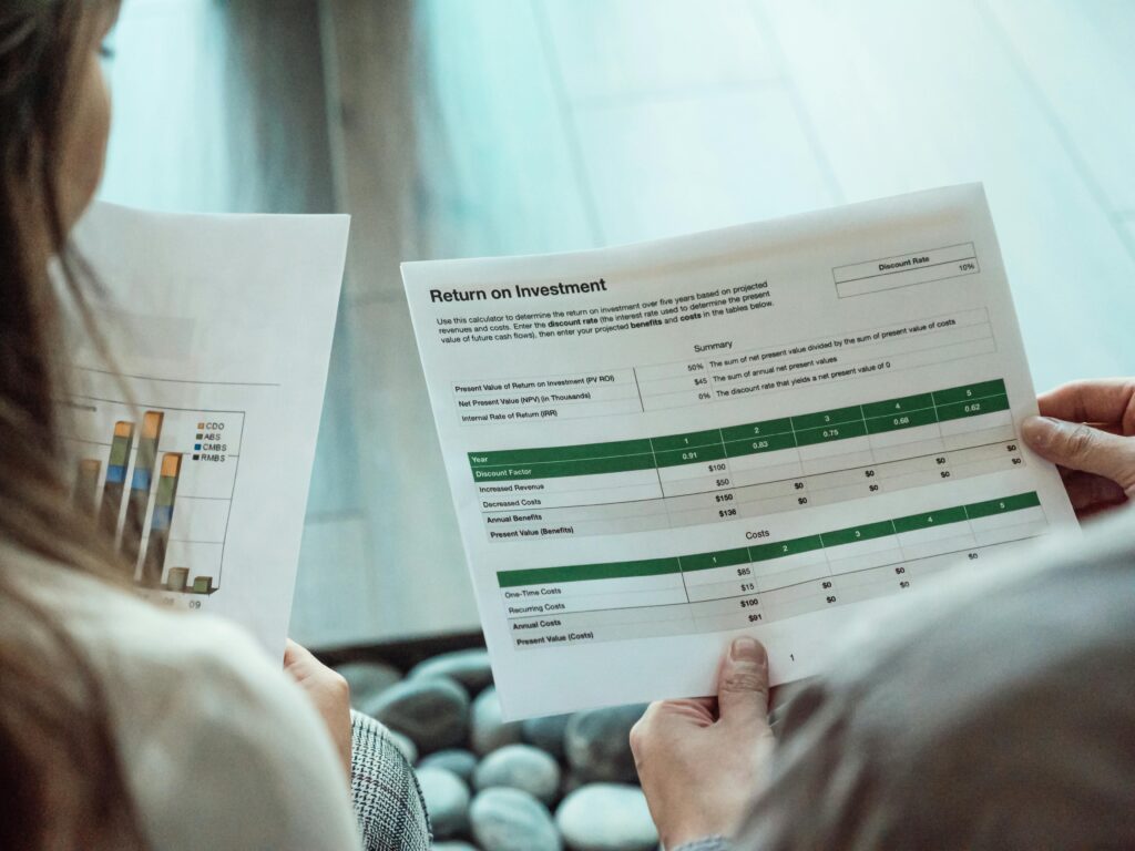 pexels-photo-7651559-7651559 Close-up of two individuals analyzing financial documents related to return on investment.